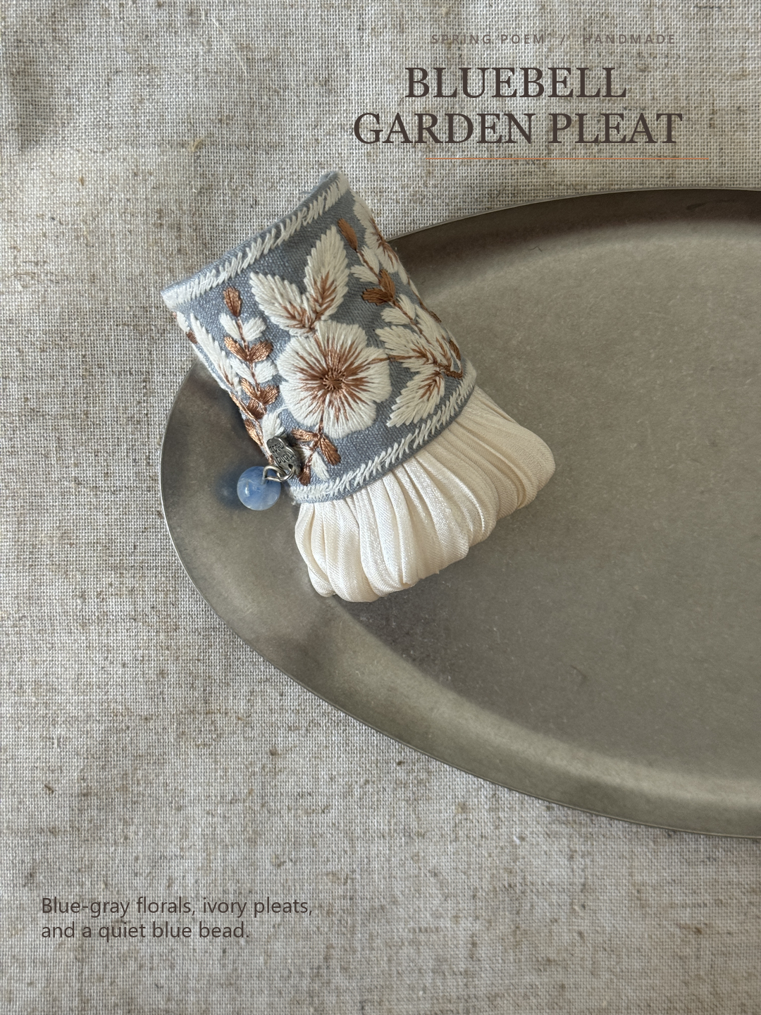 Editorial hero for Bluebell Garden Pleat showing the blue-gray floral cuff and ivory pleats