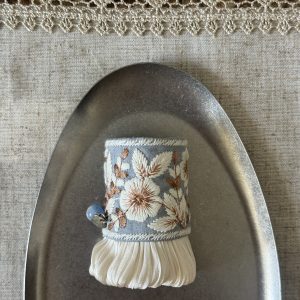 Front view of Bluebell Garden Pleat blue-gray floral hair cuff with ivory embroidery, pleats and a blue bead accent