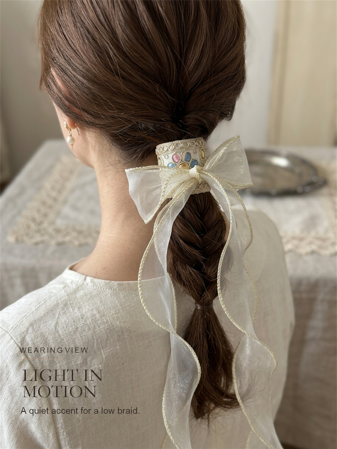 Ivory Ribbon Reverie wearing view on a low braid with airy ribbon movement