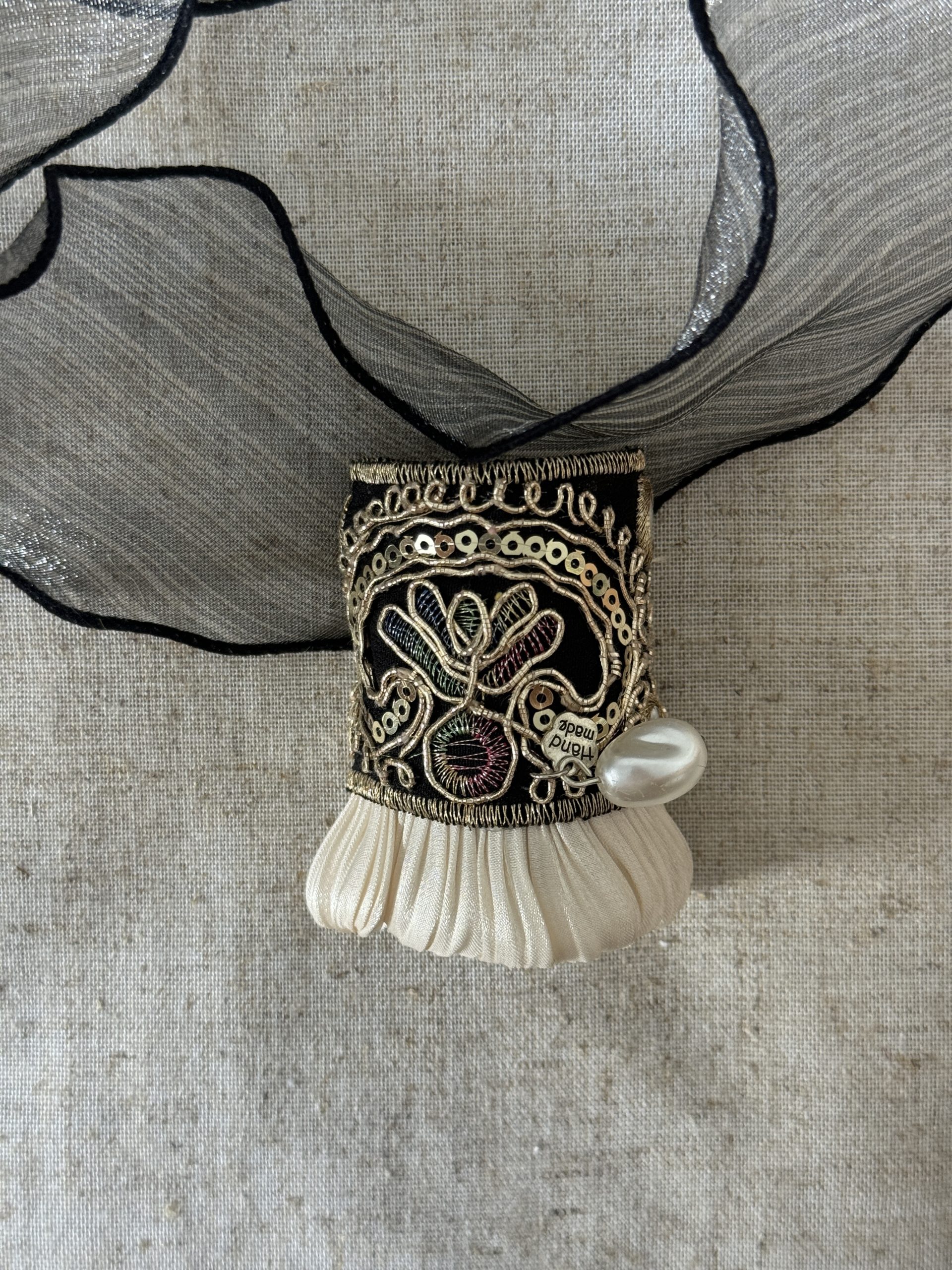 Front view of the Midnight Gold Pleat hair cuff with charcoal ribbon, gold embroidery and ivory pleats
