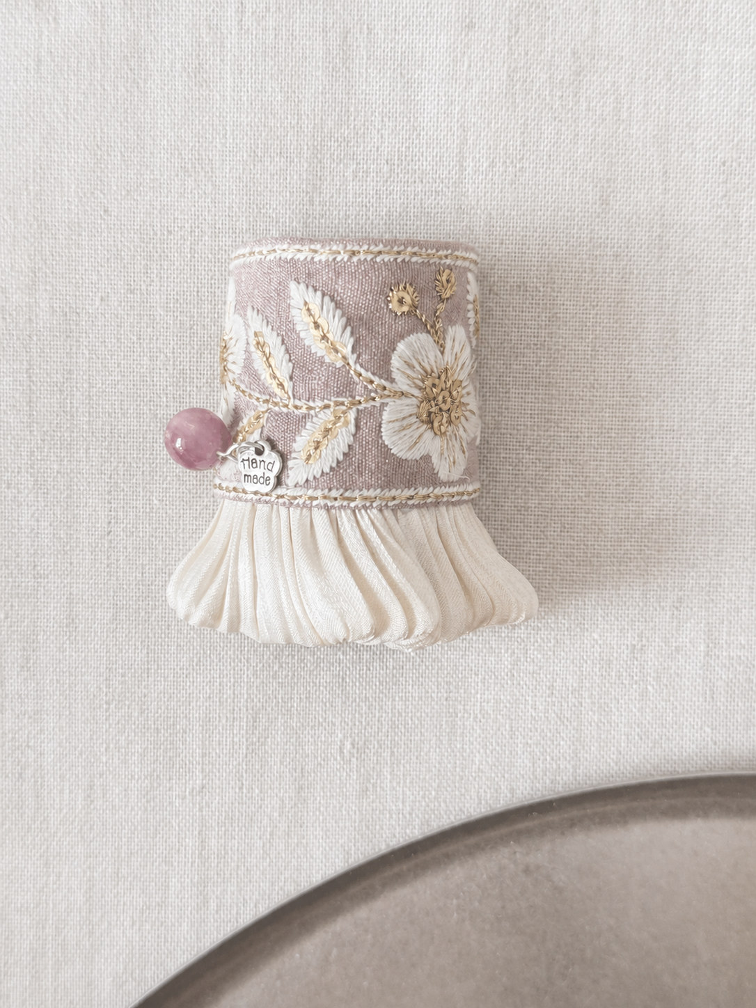 Front detail of Rosewood Bloom Pleat embroidery and ivory pleats