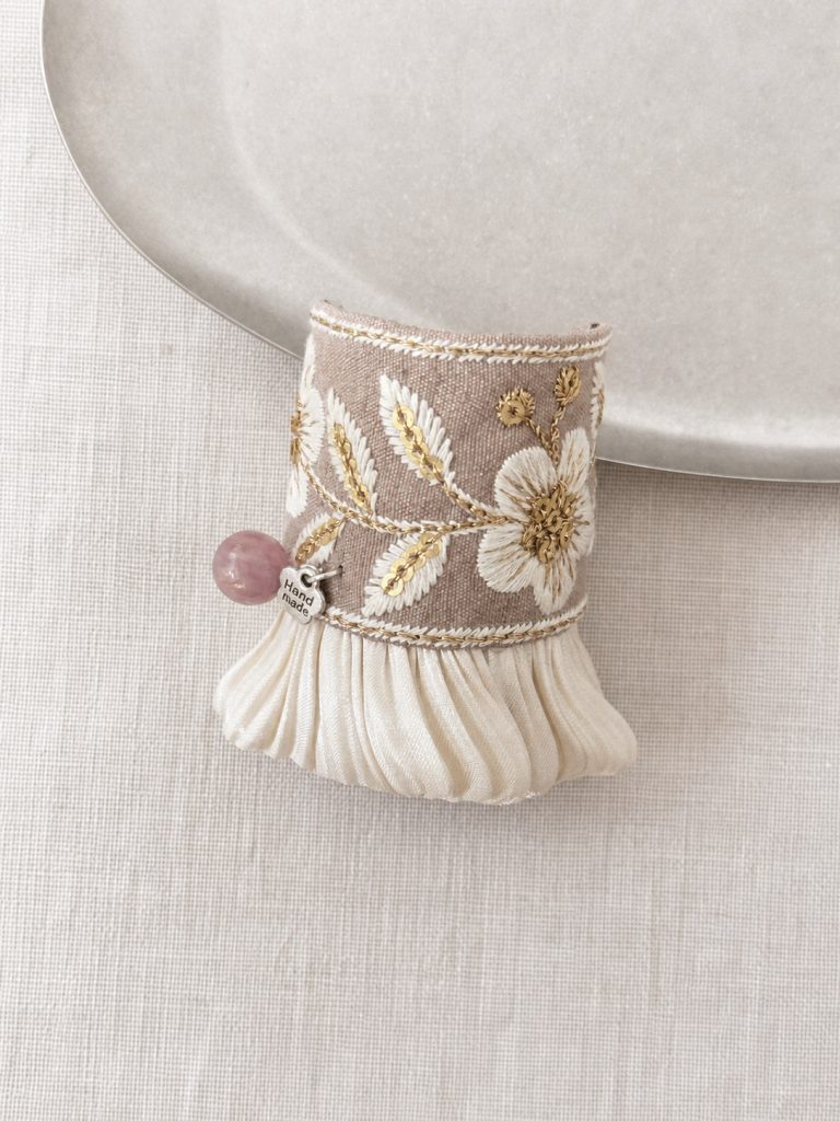 Close-up of cream floral embroidery and plum bead accent