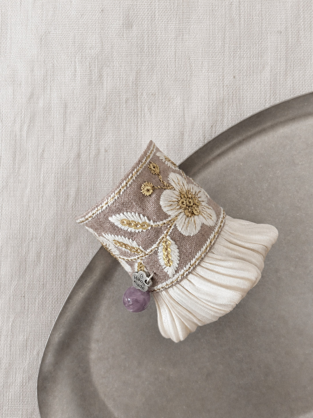 Detailed view of gold thread and hand-shaped ivory pleats